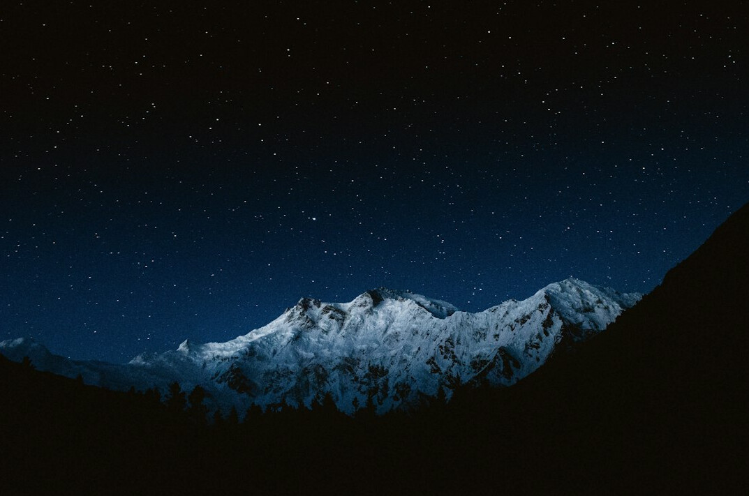 Starry night sky above dark mountains